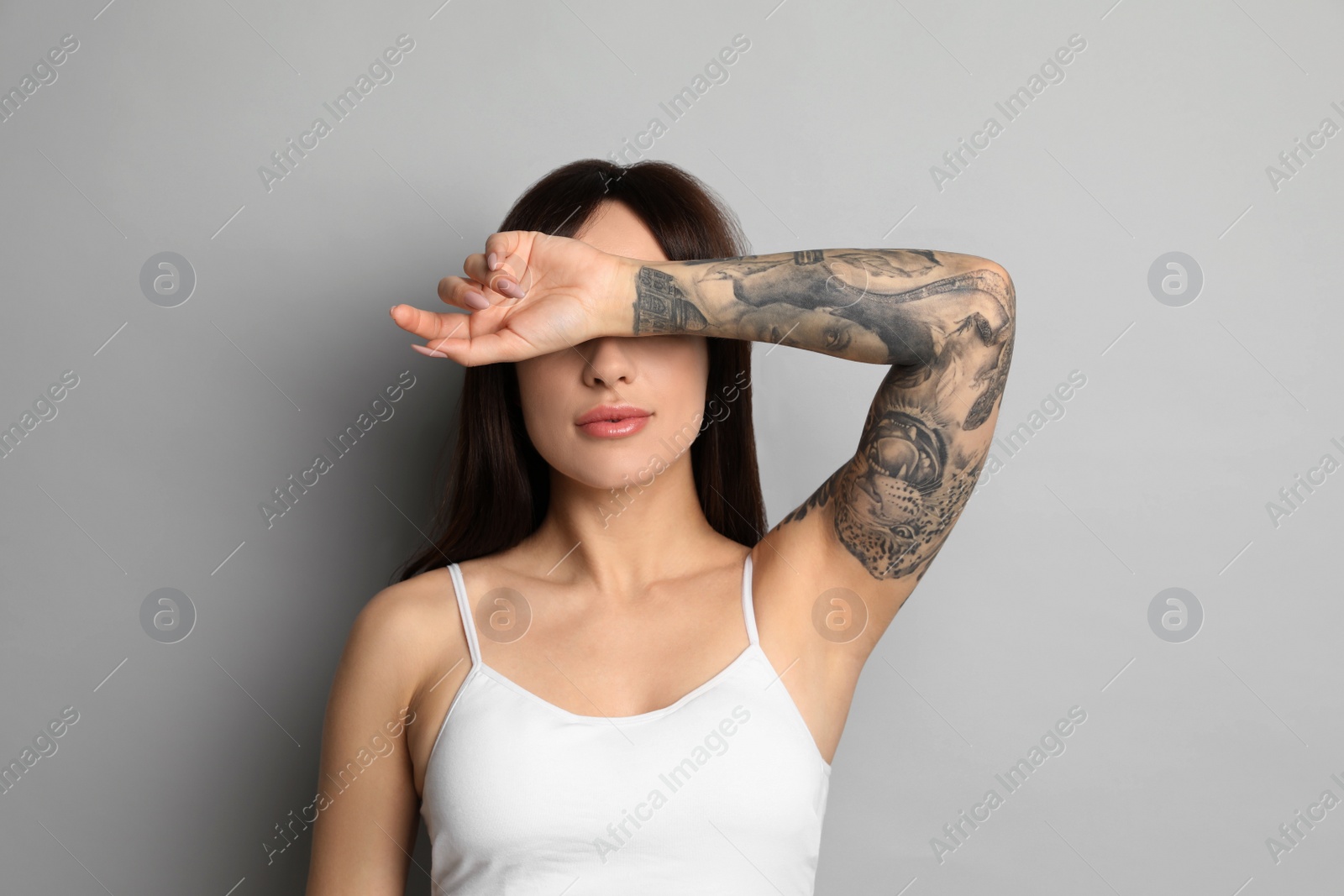 Photo of Beautiful woman with tattoos on arm against grey background