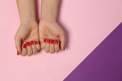 Woman showing red manicure on color background, top view with space for text. Nail polish trends