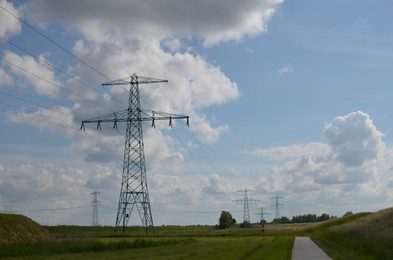 Photo of Modern high voltage towers in field on sunny day