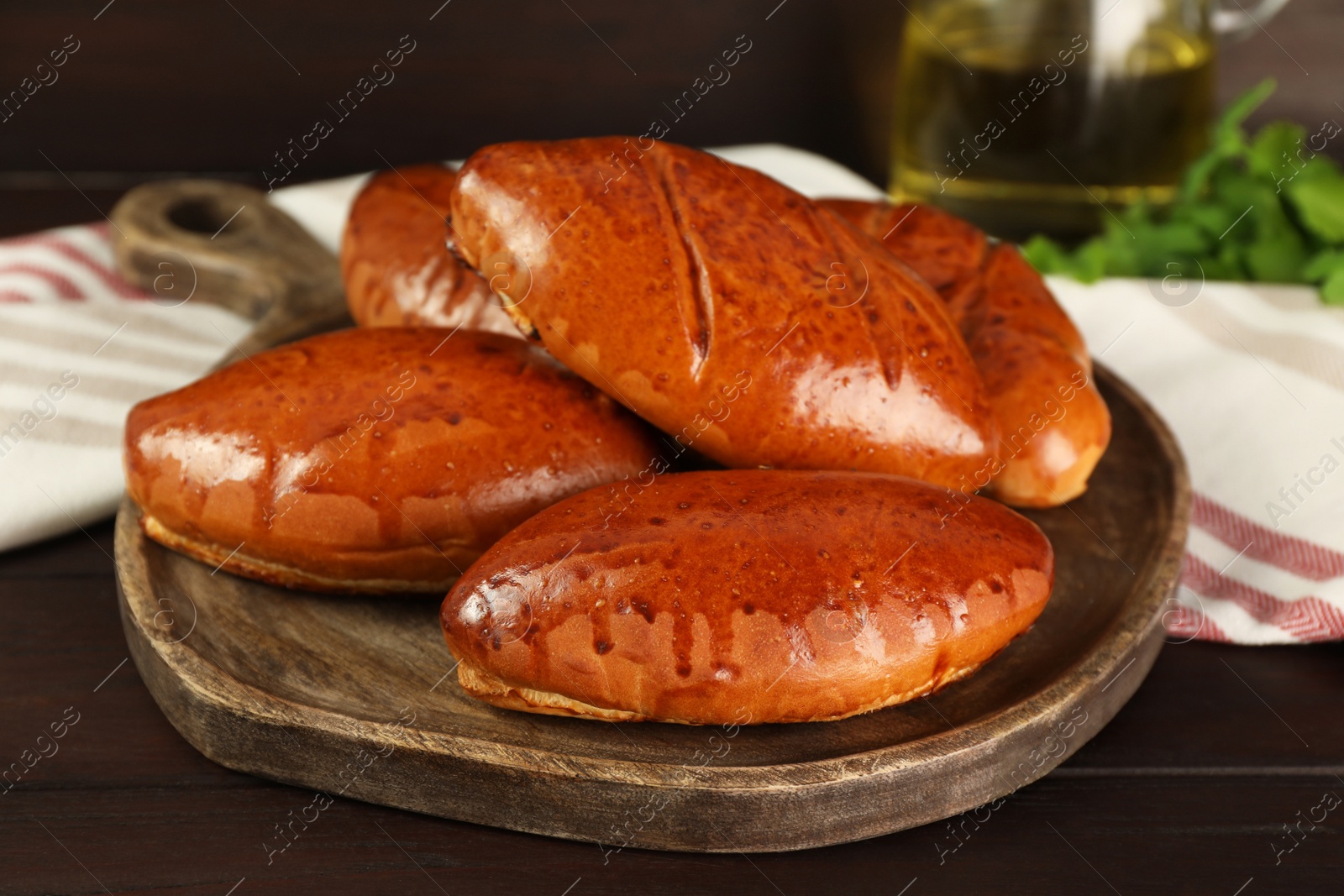 Photo of Delicious baked pirozhki on wooden table, closeup