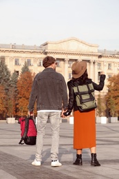 Photo of Couple of travelers with backpacks on city street, back view