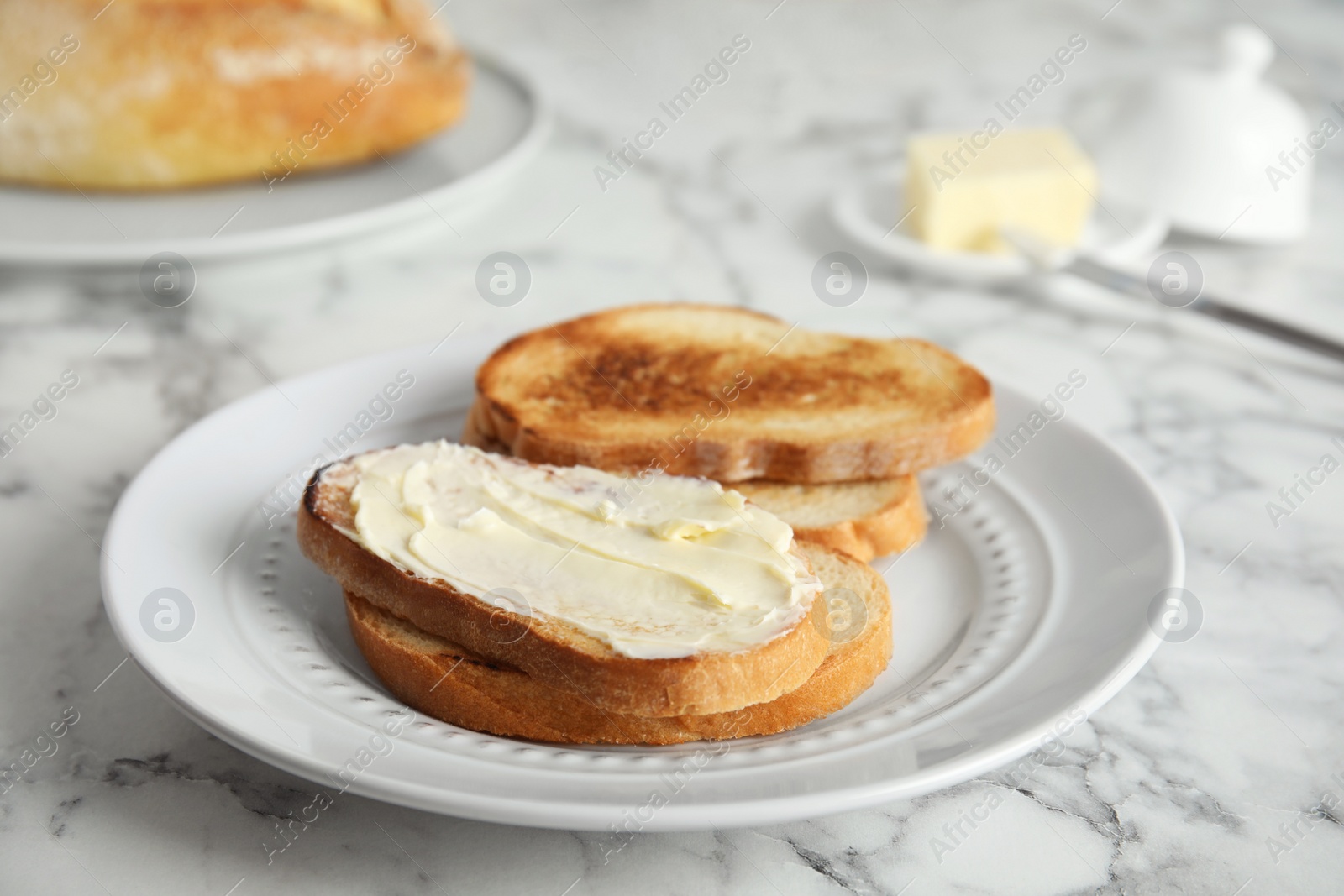 Photo of Tasty bread with butter served for breakfast on marble table