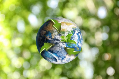 Image of Recycling concept. Earth planet with green arrows and leaves on blurred background, illustration