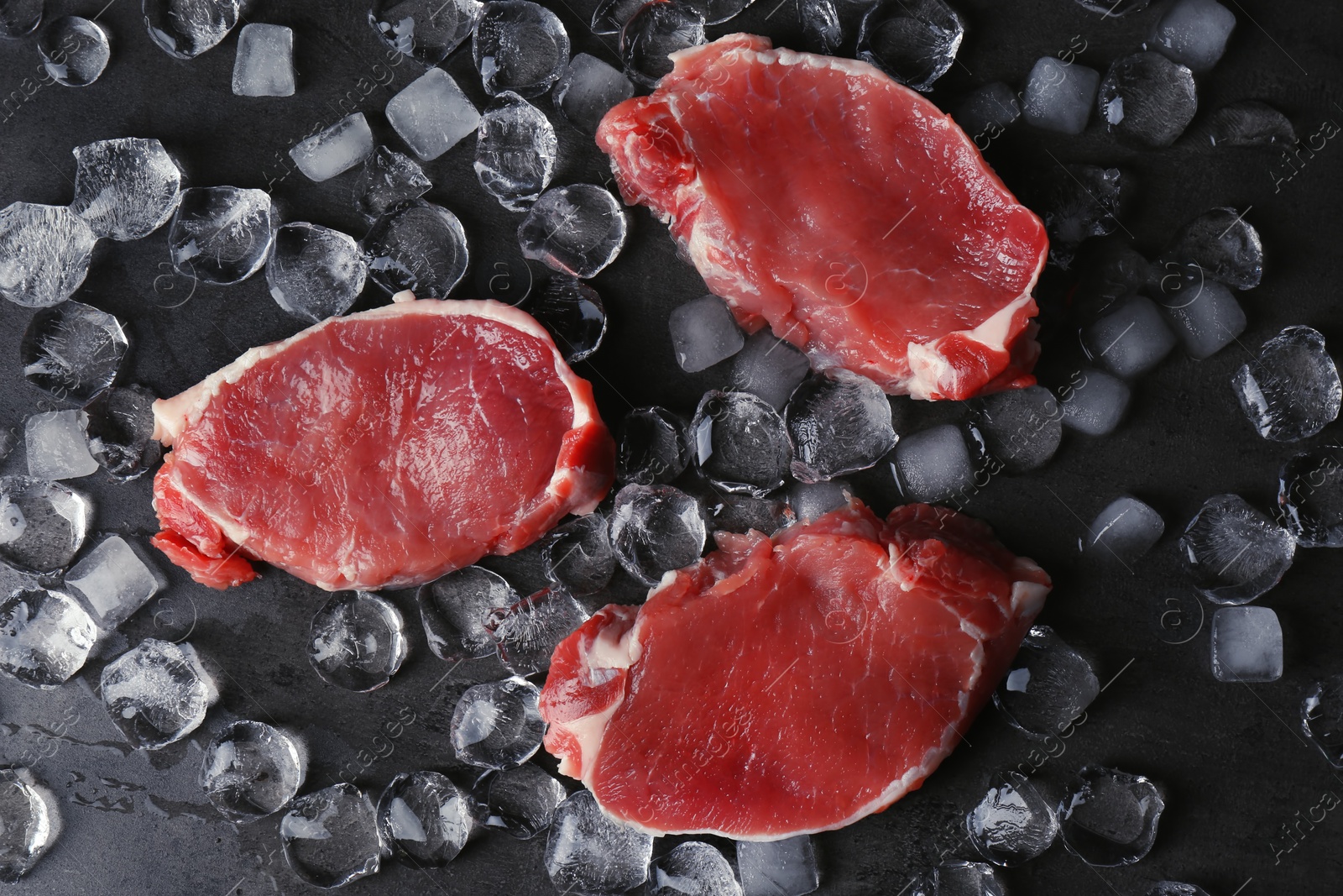 Photo of Flat lay composition with raw meat and ice cubes on dark background