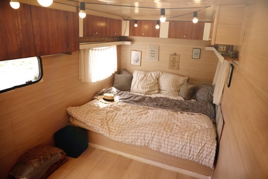 Stylish room interior with comfortable bed and pillows in modern trailer. Camping vacation