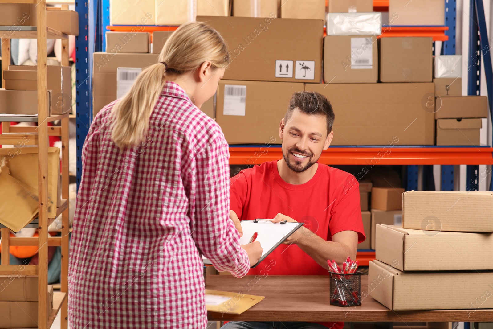 Photo of Woman signing papers for delivered parcel at post office