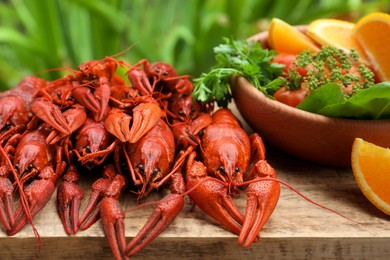 Delicious red boiled crayfish and products in bowl on wooden table