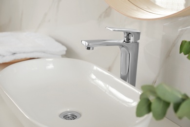 Photo of Vessel sink with shiny faucet in bathroom interior