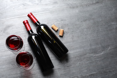 Photo of Glasses and bottles with red wine on color background, flat lay. Space for text
