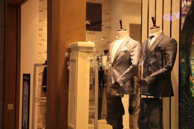 Photo of Beautiful suits on mannequins in showcases of fashion store