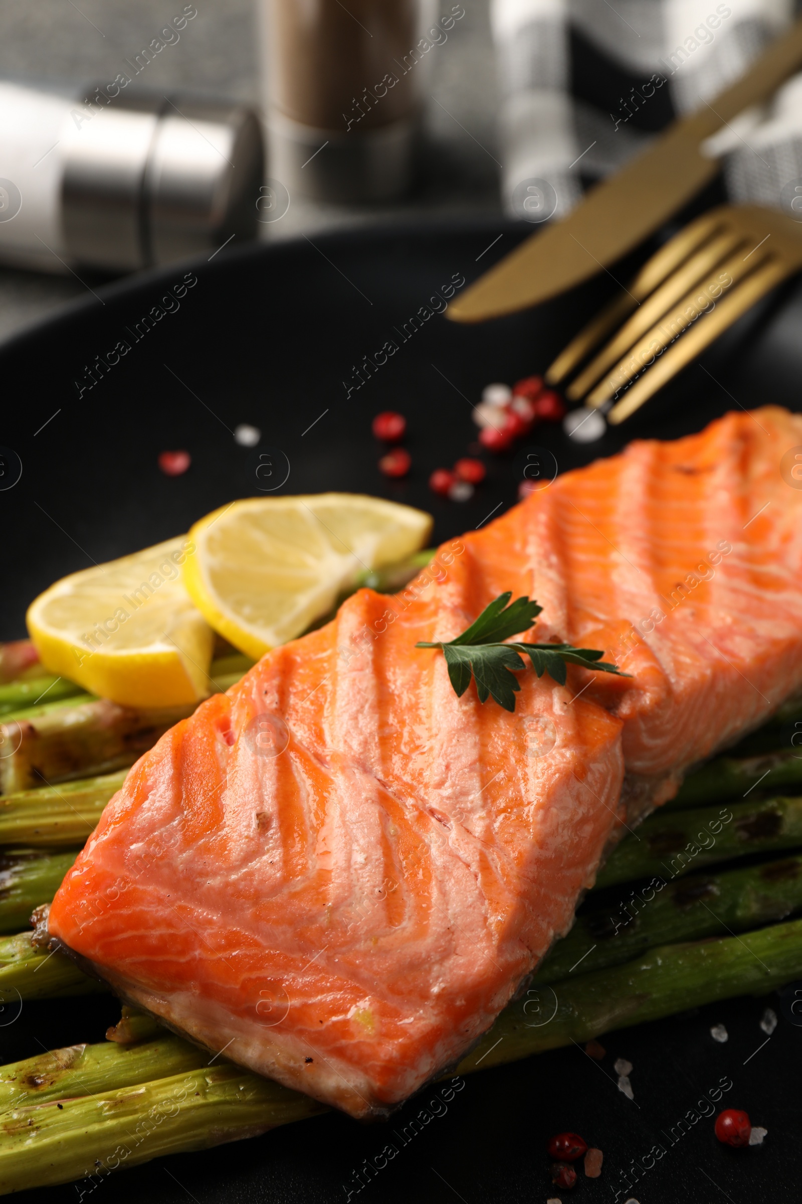 Photo of Tasty grilled salmon with asparagus and spices served on table, closeup