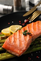 Tasty grilled salmon with asparagus and spices served on table, closeup