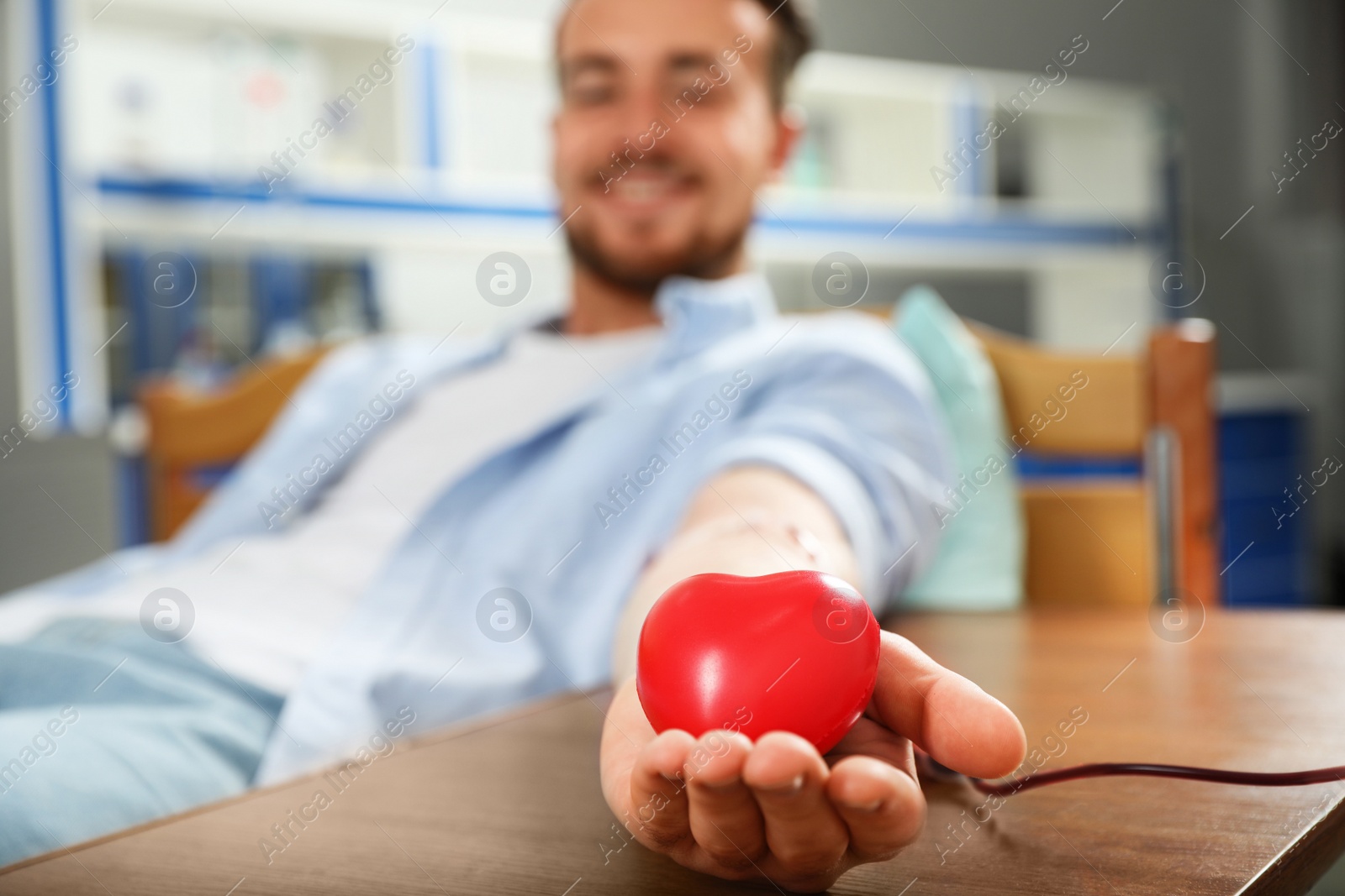 Photo of Young man making blood donation in hospital, focus on hand