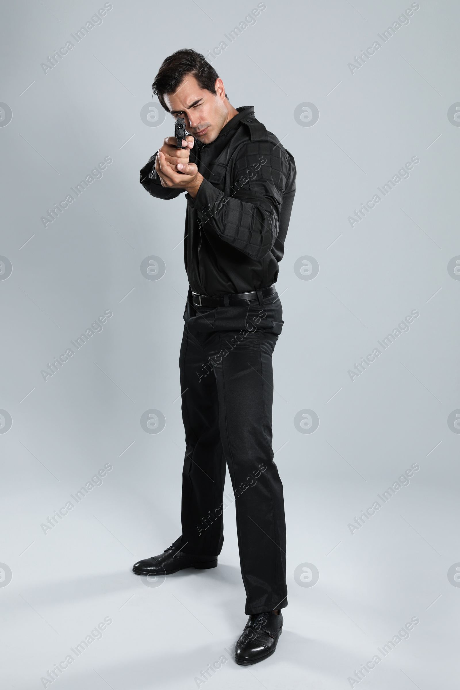 Photo of Male security guard in uniform with gun on grey background