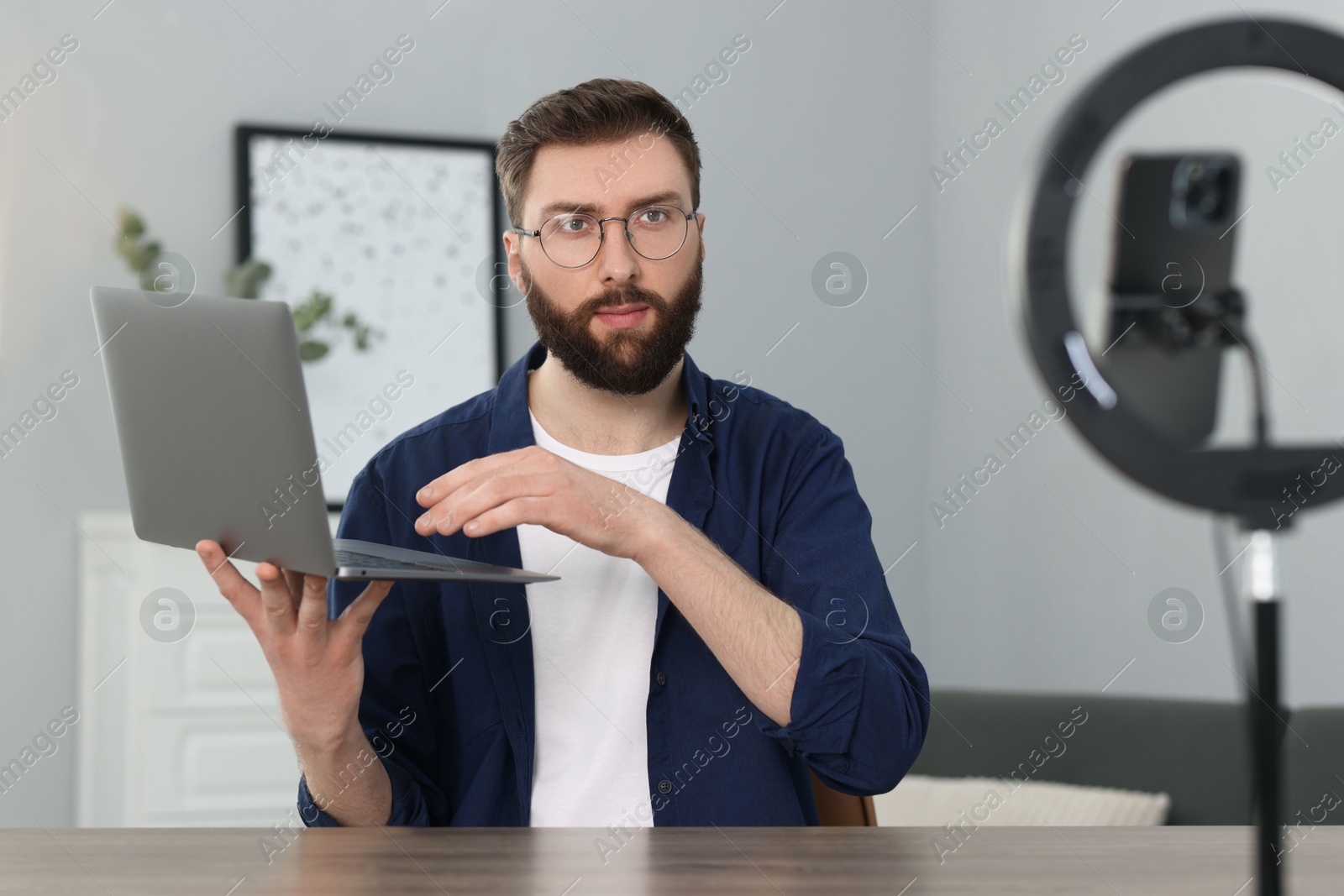 Photo of Technology blogger with laptop recording video review at home