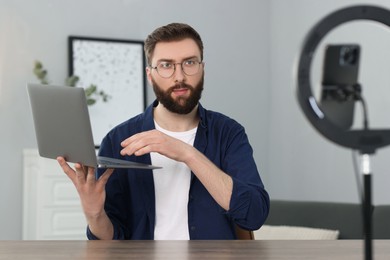 Technology blogger with laptop recording video review at home