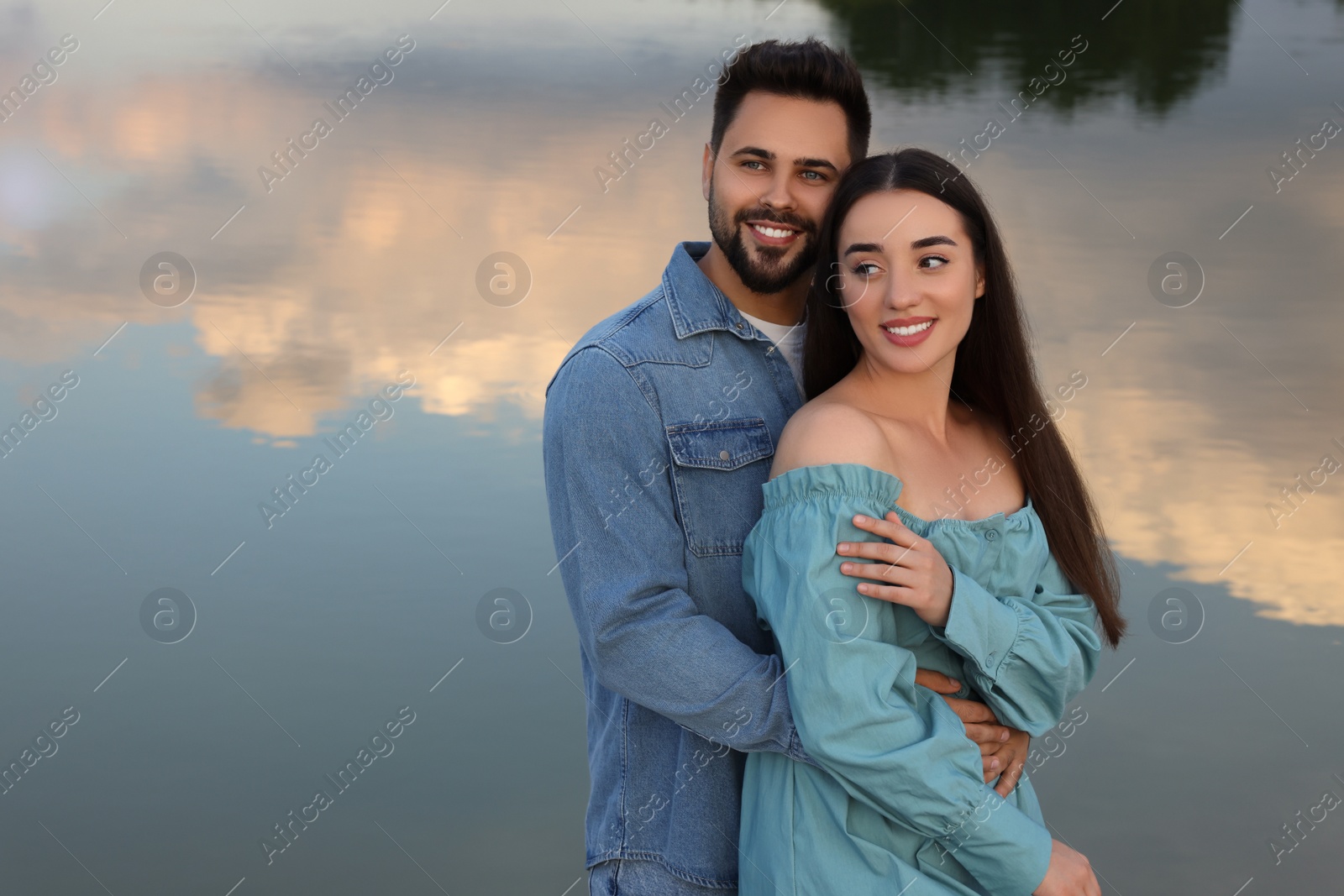 Photo of Romantic date. Beautiful couple spending time together near lake, space for text