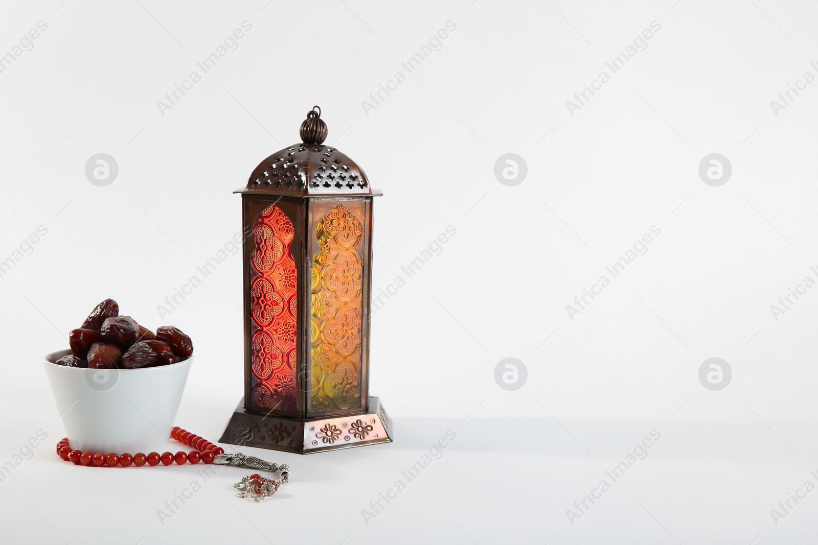 Photo of Muslim lamp, dates and prayer beads on white background. Space for text