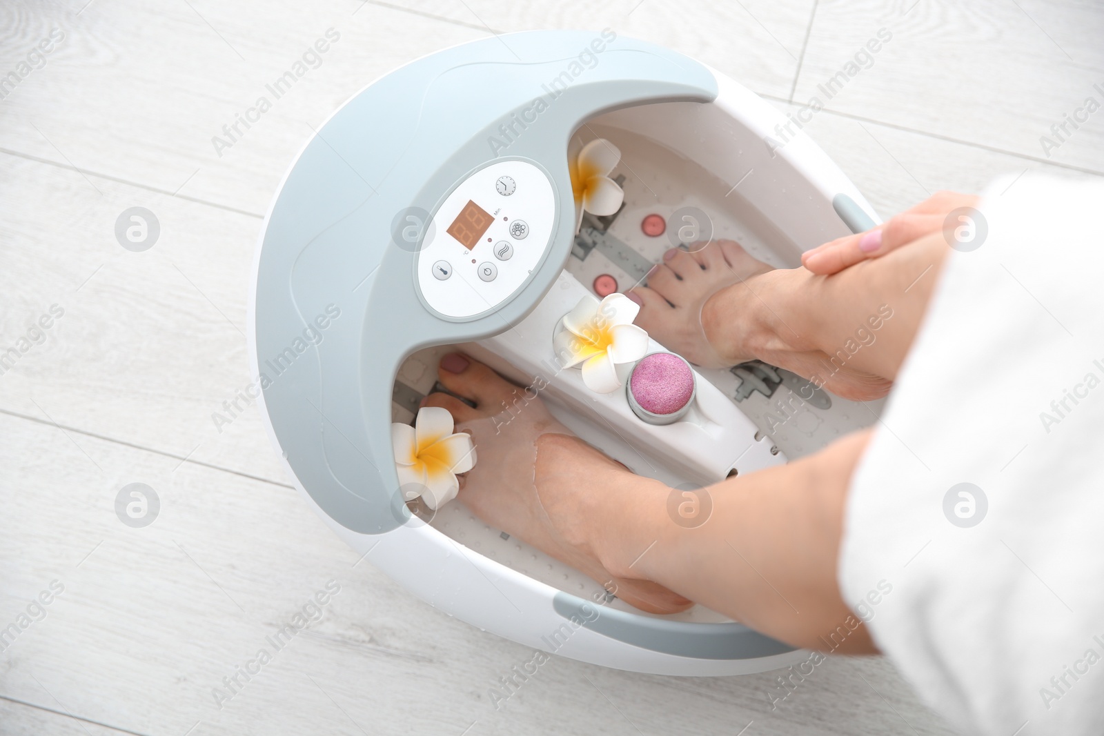 Photo of Woman with beautiful legs using foot bath at home, closeup. Spa treatment