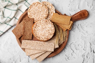 Photo of Rye crispbreads, rice cakes and rusks on white textured table, flat lay