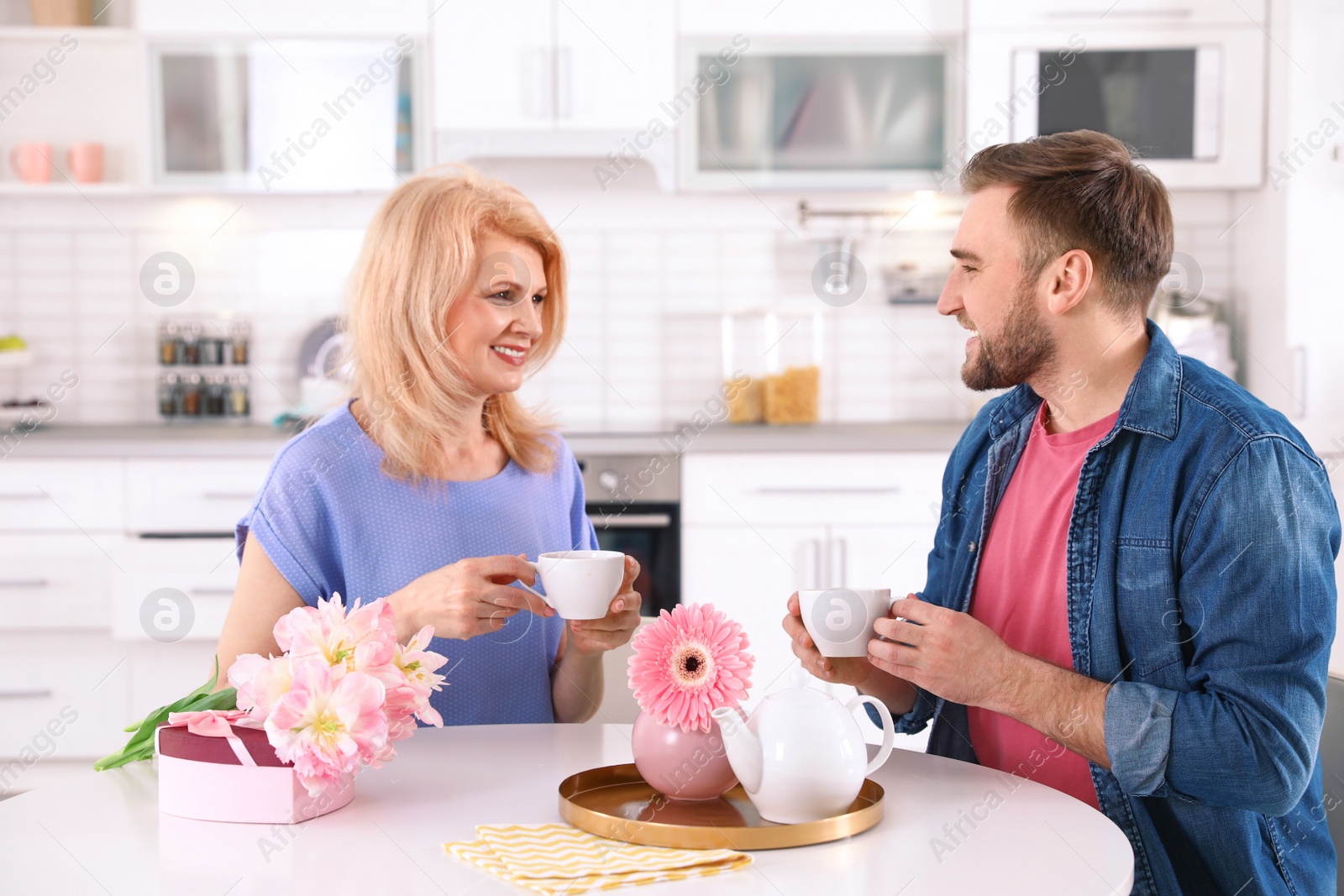 Photo of Young man and his mature mom having breakfast in kitchen. Happy Mother's Day