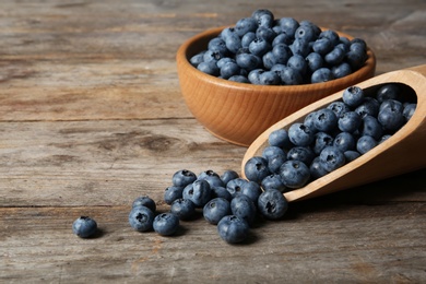 Photo of Dishware with juicy and fresh blueberries on wooden table