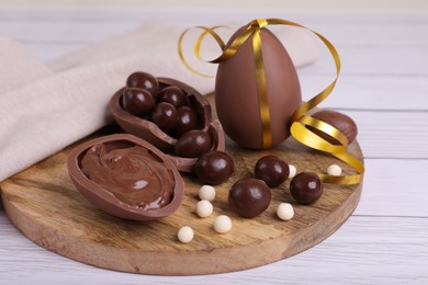 Photo of Composition with delicious chocolate eggs and candies on white wooden table, closeup