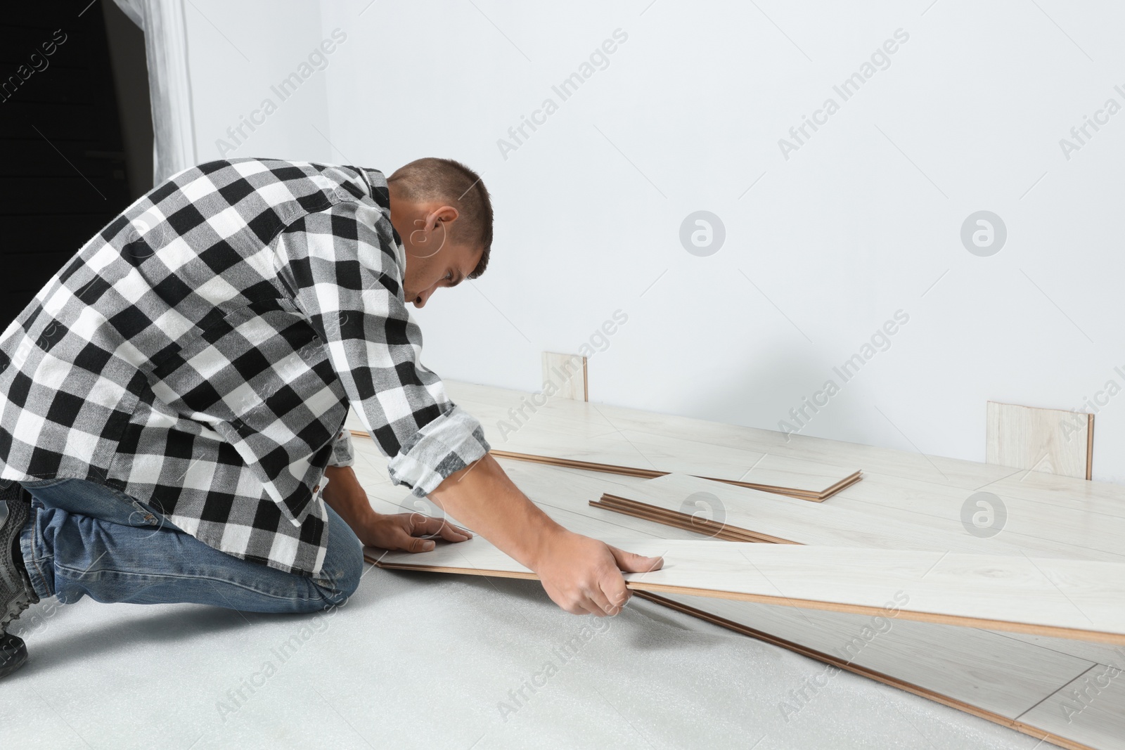 Photo of Professional worker installing new laminate flooring indoors