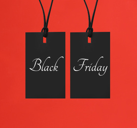 Tags with text BLACK FRIDAY on red background, flat lay 