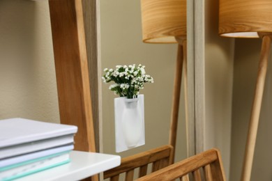Silicone vase with beautiful white flowers on mirror in room