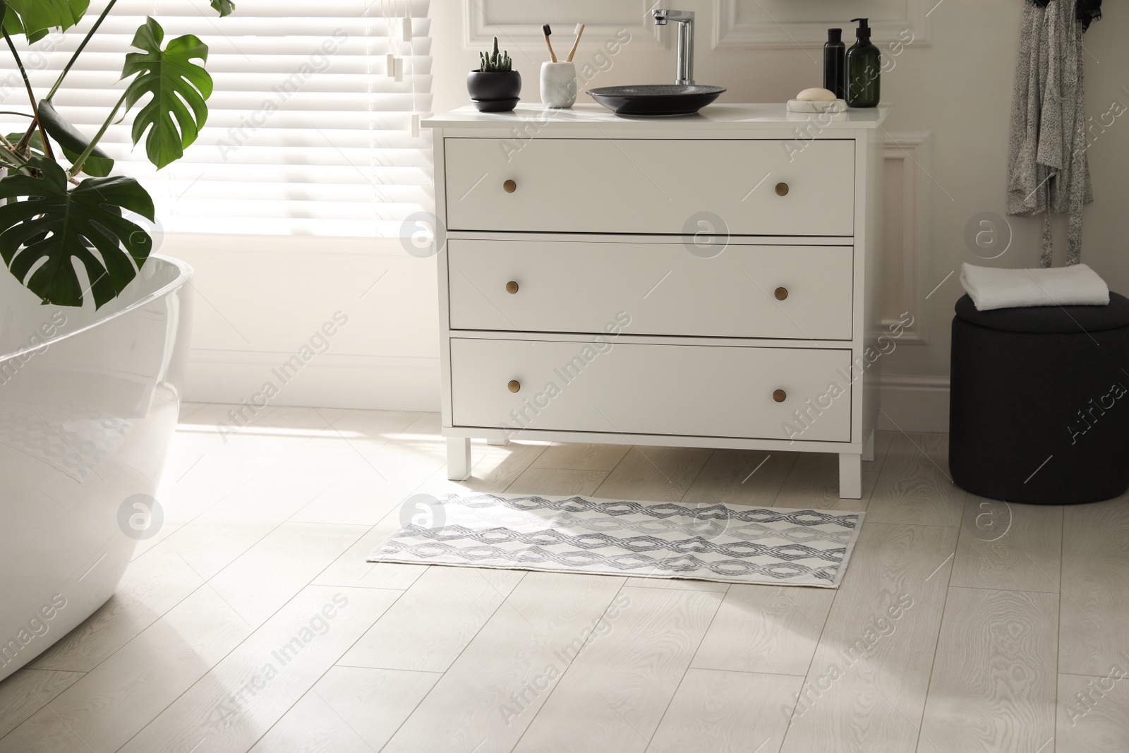 Photo of Stylish mat with pattern near chest of drawers in bathroom