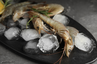 Photo of Raw shrimps with ice on grey table, closeup