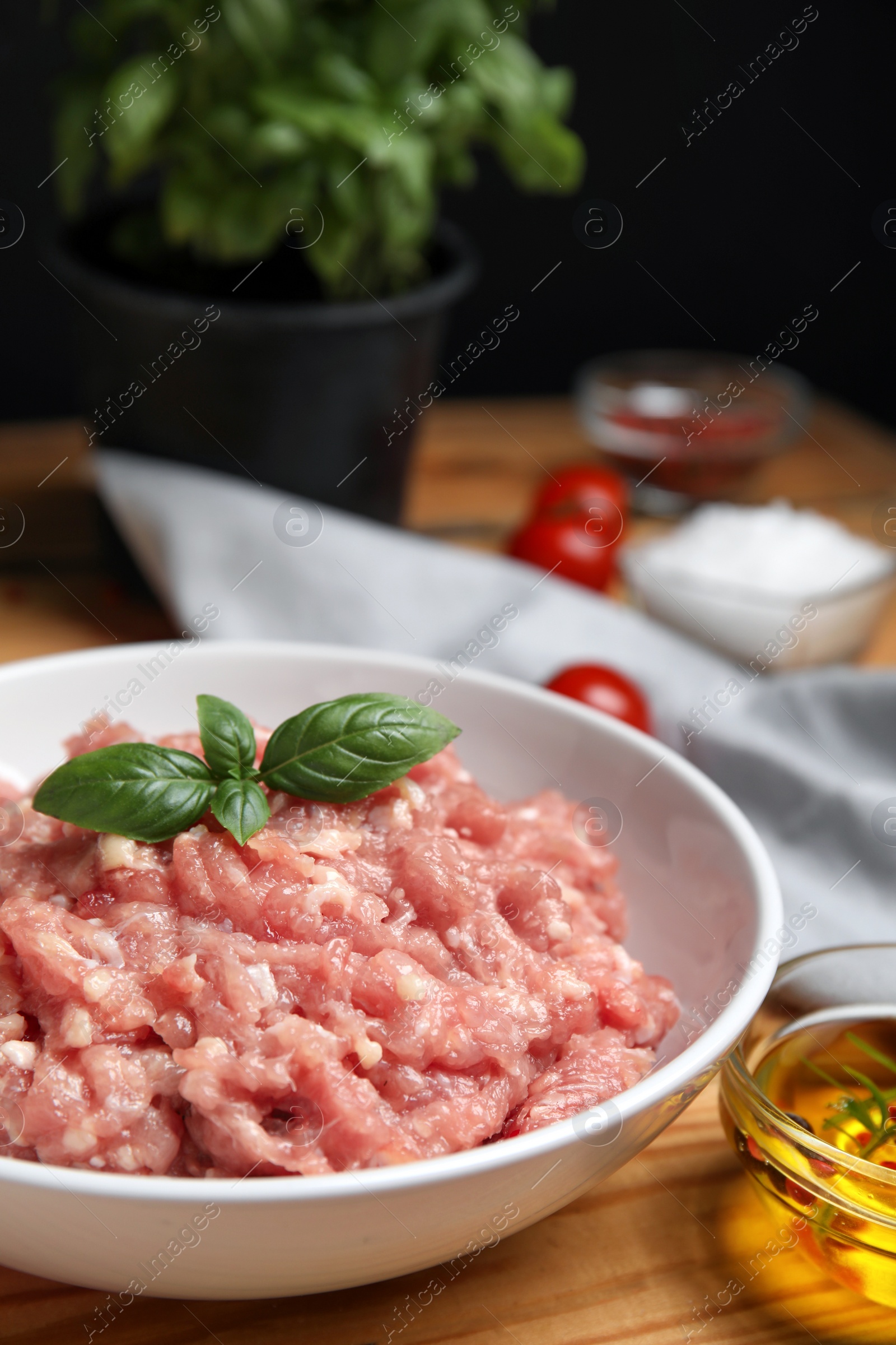 Photo of Raw chicken minced meat with basil on wooden table, closeup