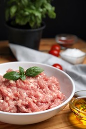 Photo of Raw chicken minced meat with basil on wooden table, closeup