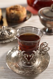 Glass of traditional Turkish tea in vintage holder on white wooden table