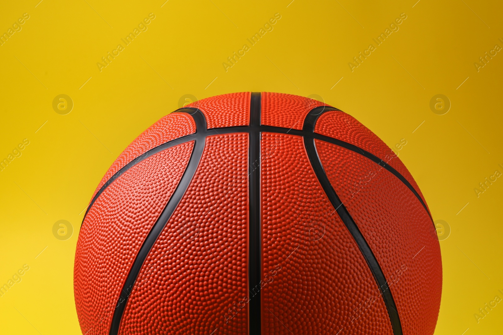 Photo of One new basketball ball on yellow background, closeup