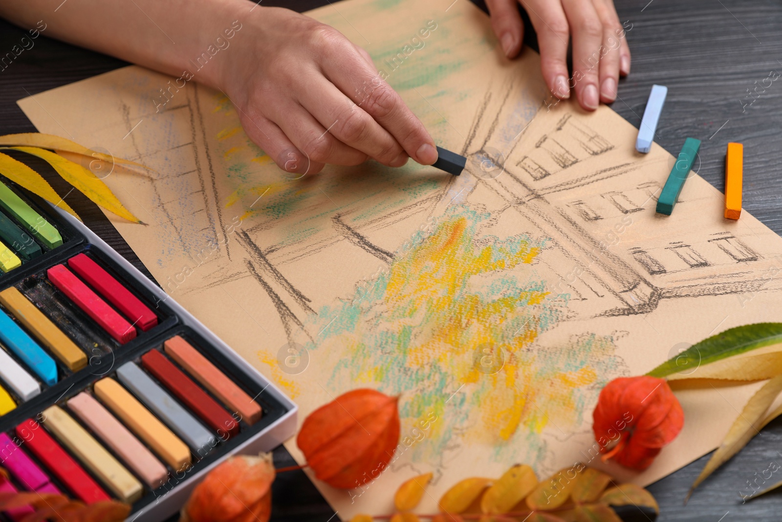 Photo of Woman drawing beautiful building with soft pastel at wooden table, closeup