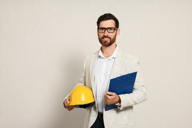 Photo of Professional engineer with hard hat and clipboard on white background