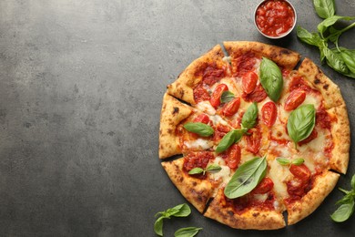 Photo of Delicious Margherita pizza, basil and tomato sauce on grey table, top view. Space for text