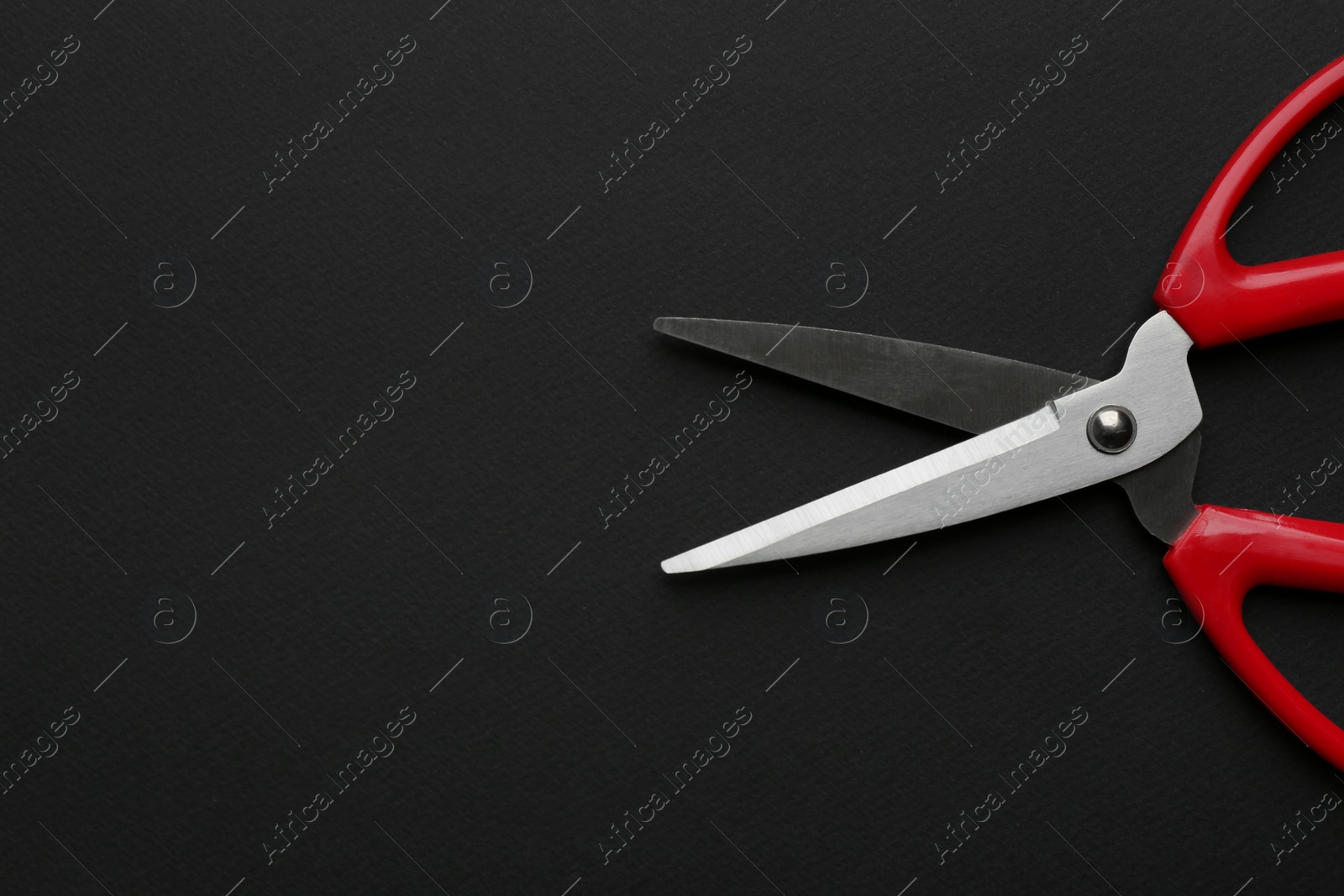 Photo of Pair of sharp scissors on dark background, top view. Space for text