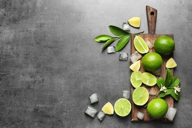 Photo of Composition with fresh ripe limes and ice cubes on gray background, top view