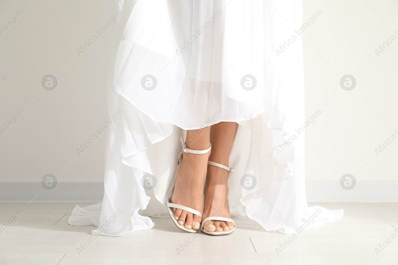 Photo of Young bride wearing beautiful wedding dress near light wall, closeup