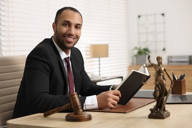 Photo of Smiling lawyer with book at table in office