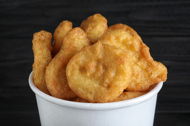 Photo of Bucket with tasty chicken nuggets on black background, closeup