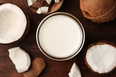 Glass o delicious vegan milk and coconut pieces on wooden table, flat lay