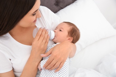 Woman feeding her baby from bottle on bed