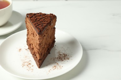 Photo of Piece of delicious chocolate truffle cake on white marble table, closeup. Space for text