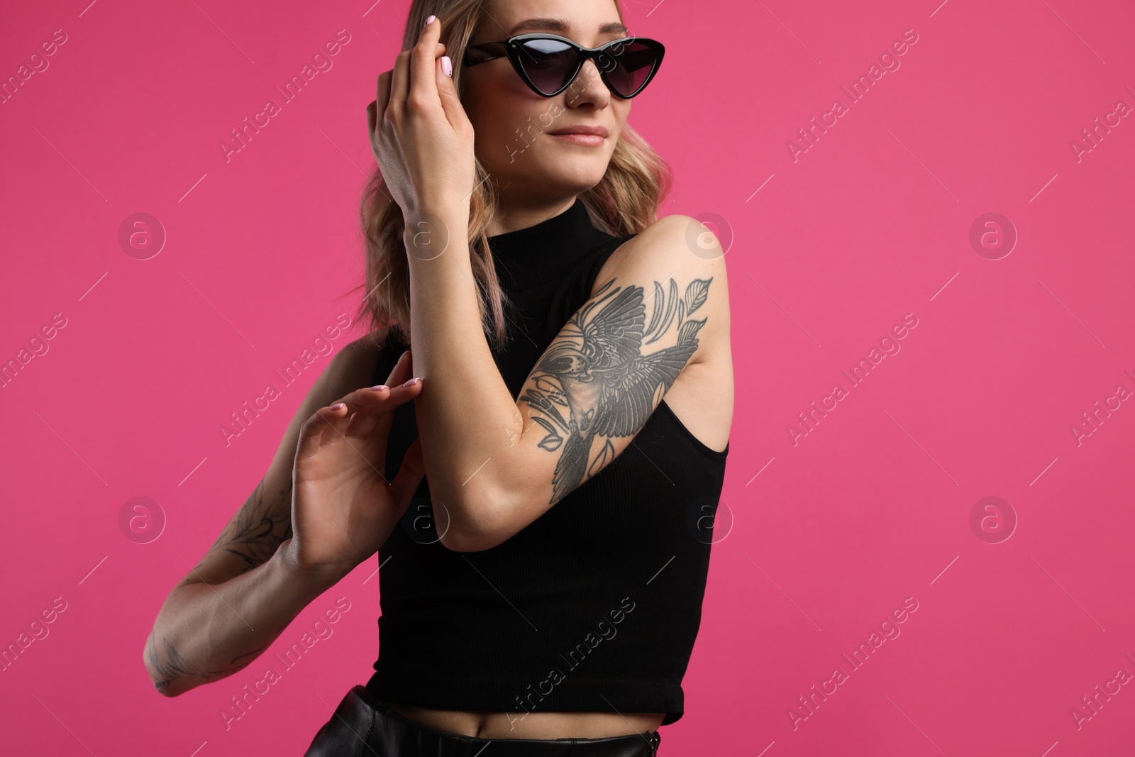 Photo of Beautiful woman with tattoos on arms against pink background. Space for text