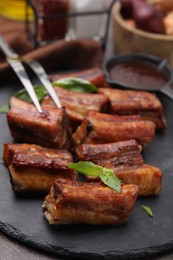 Tasty roasted pork ribs served with basil on table, closeup