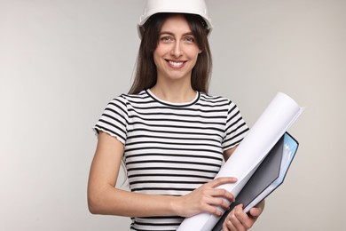 Photo of Architect in hard hat with draft and folder on light grey background